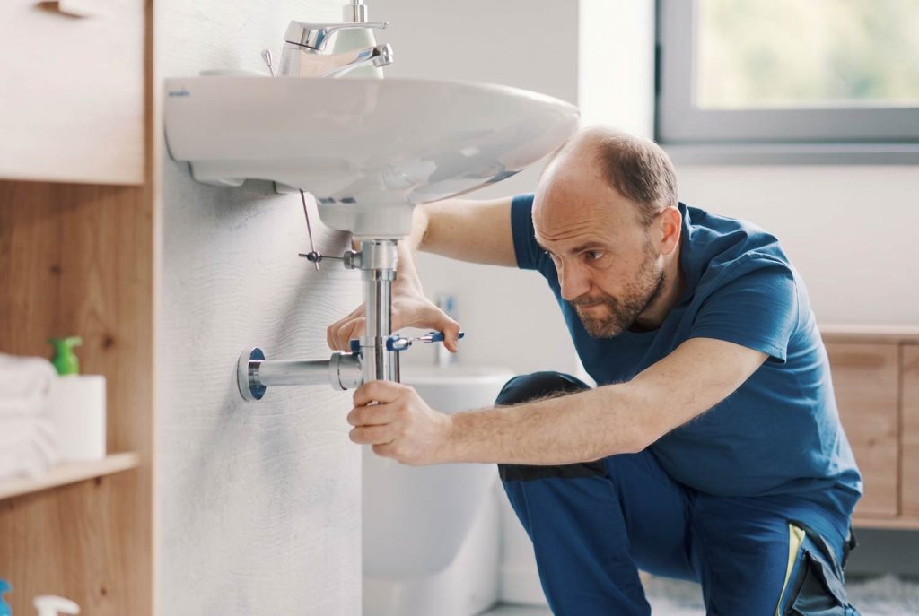 Property maintenance technician repairing plumbing